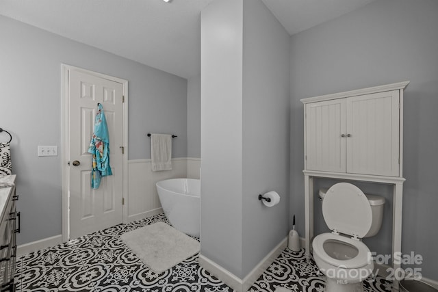 bathroom featuring toilet, vanity, tile patterned floors, and a tub to relax in