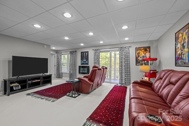 carpeted living room featuring a drop ceiling and a healthy amount of sunlight