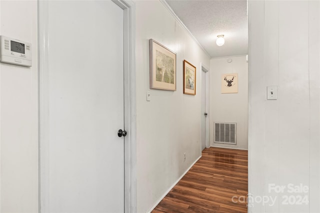 corridor featuring dark hardwood / wood-style flooring, crown molding, and a textured ceiling