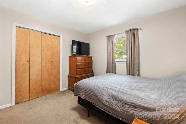 carpeted bedroom with a textured ceiling and a closet