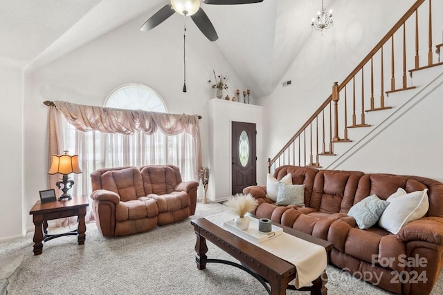 carpeted living room featuring ceiling fan with notable chandelier and high vaulted ceiling