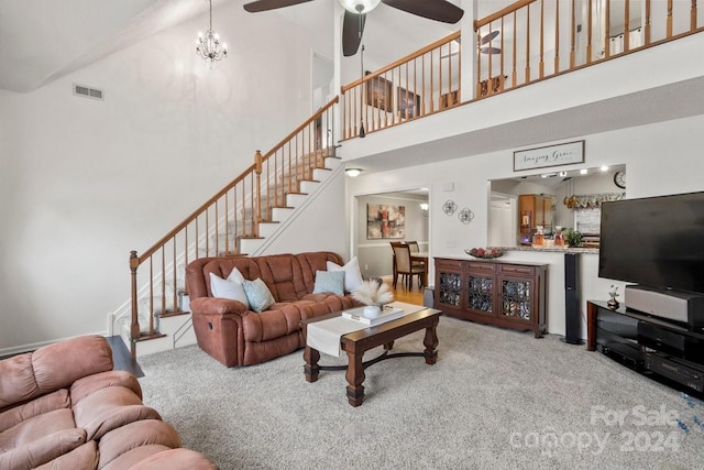 carpeted living room with ceiling fan with notable chandelier and high vaulted ceiling