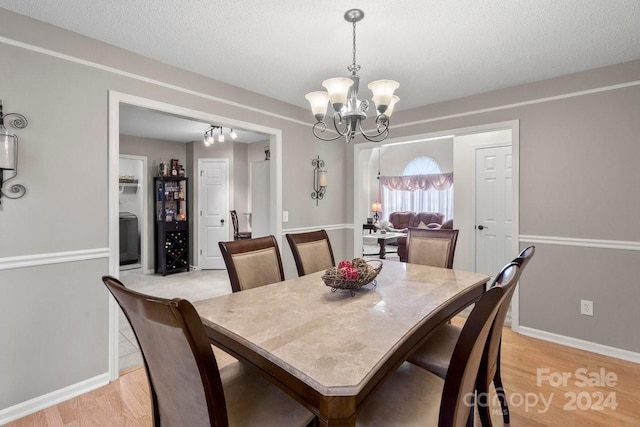 dining space featuring a textured ceiling, light hardwood / wood-style flooring, and an inviting chandelier