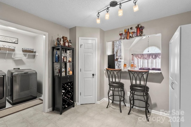 kitchen with a textured ceiling, a breakfast bar, and independent washer and dryer