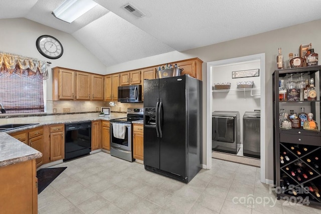 kitchen featuring a textured ceiling, black appliances, washer and clothes dryer, sink, and lofted ceiling