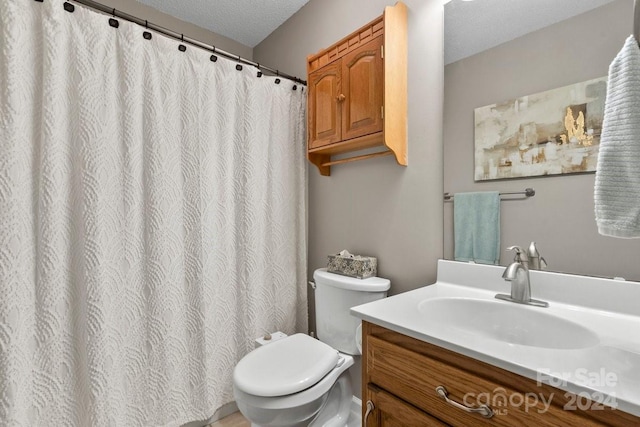 bathroom featuring toilet, a textured ceiling, and vanity