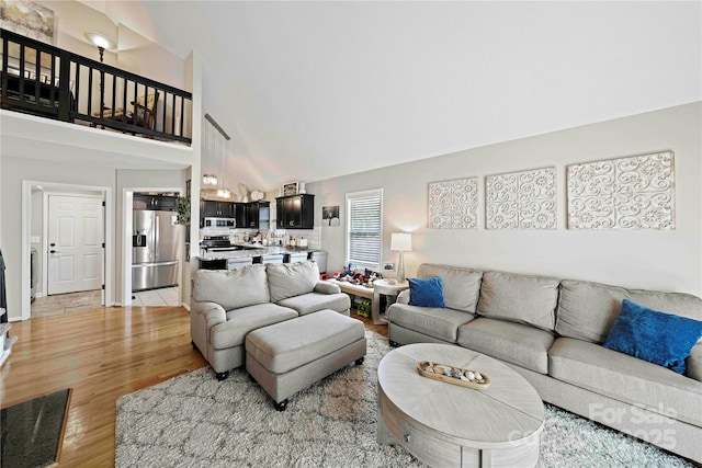 living room with light hardwood / wood-style flooring and high vaulted ceiling