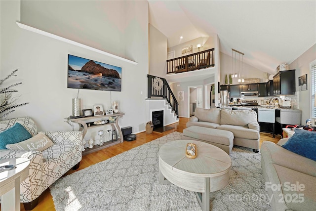 living room with light hardwood / wood-style floors and high vaulted ceiling