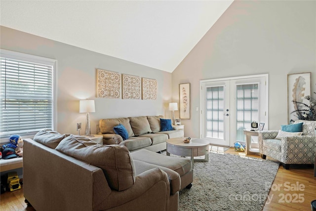 living room featuring french doors, high vaulted ceiling, and light hardwood / wood-style floors