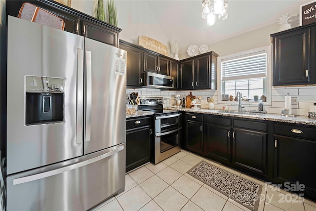 kitchen featuring light stone countertops, sink, tasteful backsplash, light tile patterned floors, and appliances with stainless steel finishes