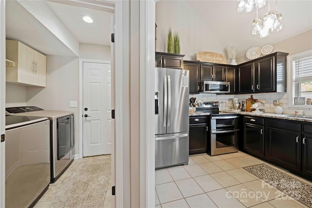 kitchen featuring decorative backsplash, separate washer and dryer, light tile patterned flooring, light stone counters, and stainless steel appliances