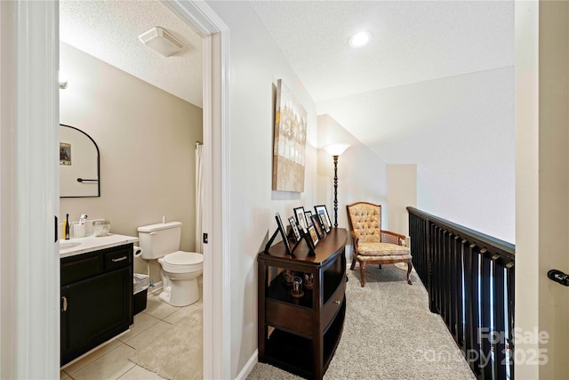 bathroom featuring a textured ceiling, vanity, vaulted ceiling, tile patterned flooring, and toilet