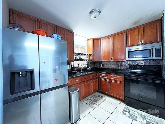 kitchen with light tile patterned floors, stainless steel appliances, sink, decorative backsplash, and dark stone countertops