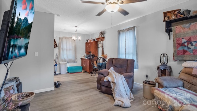 living room with a textured ceiling, ceiling fan with notable chandelier, and light hardwood / wood-style flooring