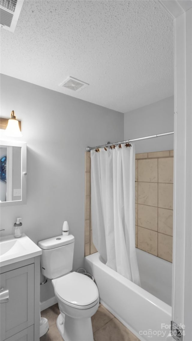 full bathroom featuring shower / bath combo, tile patterned floors, a textured ceiling, toilet, and vanity