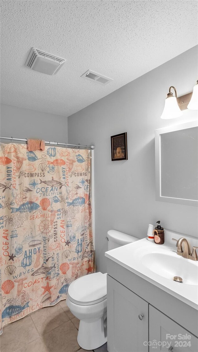 bathroom featuring a shower with curtain, tile patterned floors, a textured ceiling, toilet, and vanity