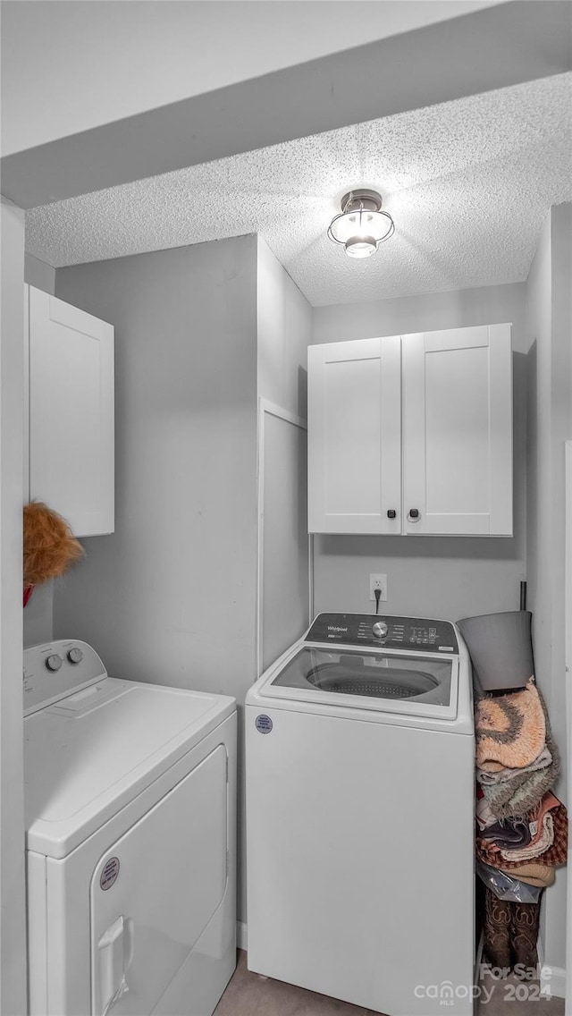 laundry area with cabinets, a textured ceiling, and separate washer and dryer