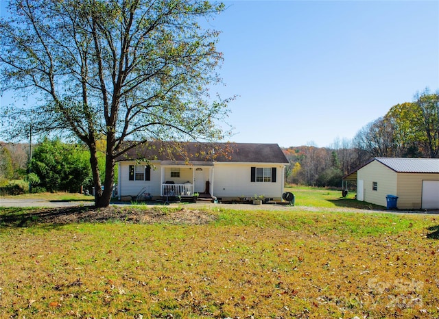 view of front of property featuring covered porch, an outbuilding, and a front yard