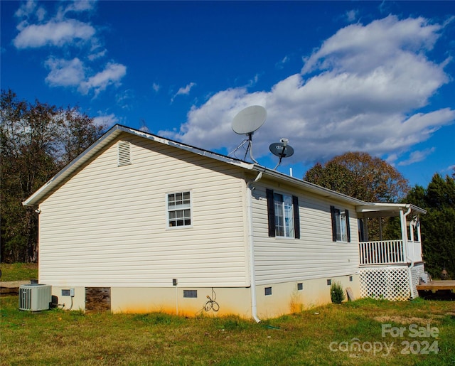 view of side of home featuring central AC unit, a porch, and a yard