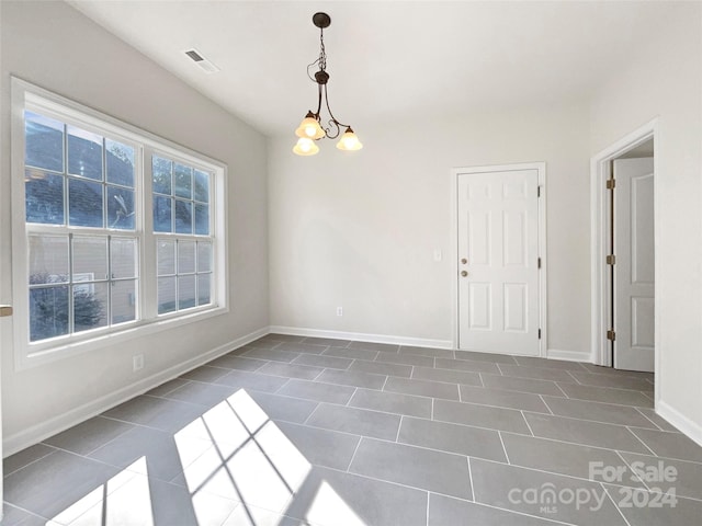 spare room featuring a chandelier and dark tile patterned floors