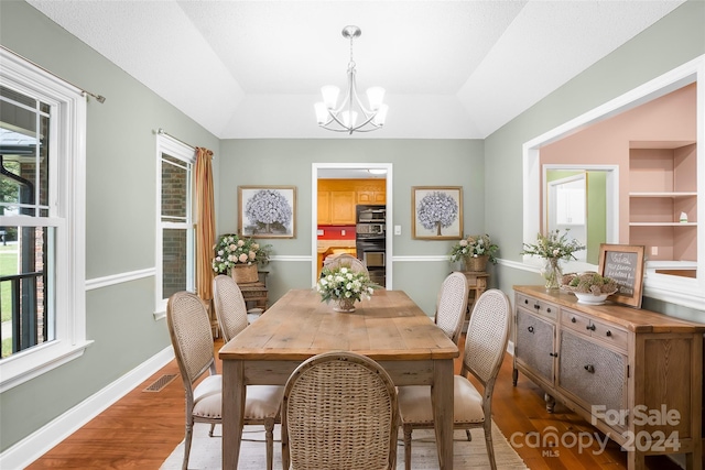 dining room featuring a raised ceiling, wood-type flooring, and a chandelier