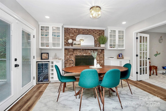 dining area with a fireplace, indoor bar, wine cooler, and light hardwood / wood-style floors