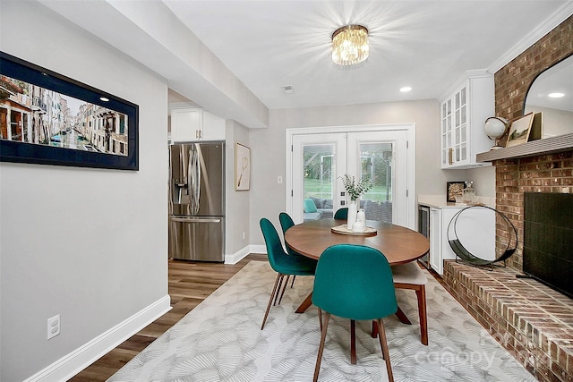 dining room with hardwood / wood-style floors, a brick fireplace, and french doors