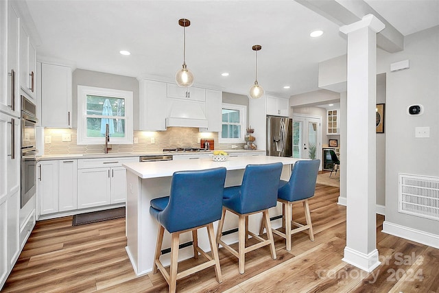 kitchen featuring a kitchen island, light hardwood / wood-style flooring, appliances with stainless steel finishes, sink, and white cabinetry