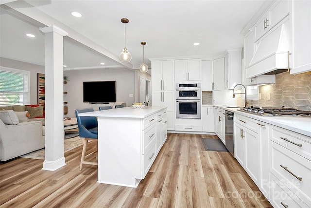 kitchen featuring light hardwood / wood-style flooring, decorative light fixtures, stainless steel appliances, white cabinetry, and sink