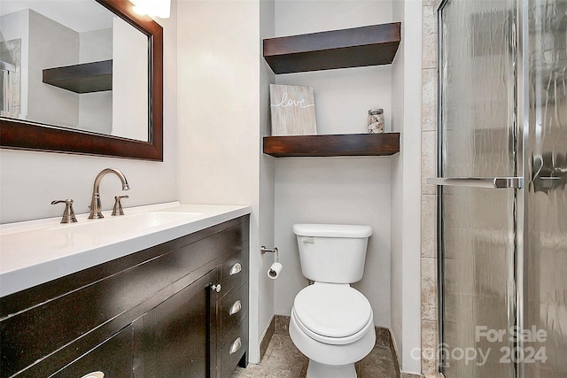 bathroom with a shower with shower door, toilet, and vanity