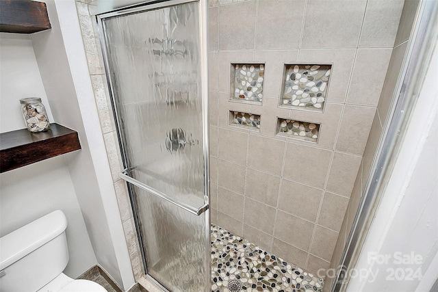 bathroom featuring toilet and a shower with shower door