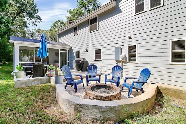 back of property featuring a patio area, a sunroom, and an outdoor fire pit