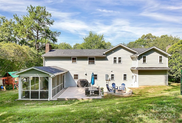 back of property with a lawn, a patio area, and a sunroom