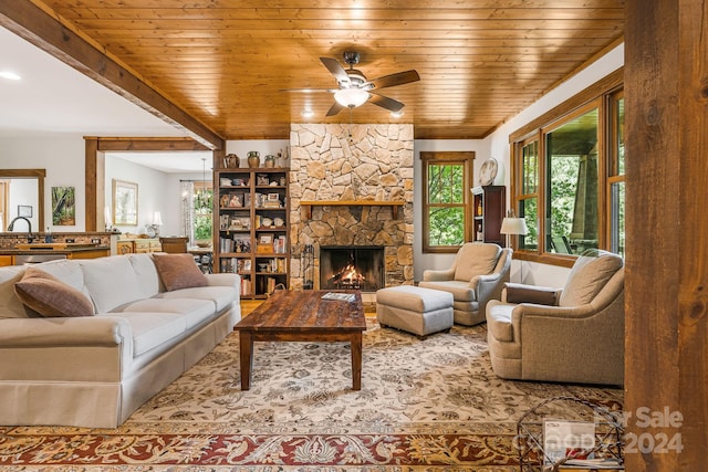 living room featuring wood ceiling, a fireplace, sink, and ceiling fan