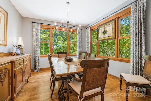 dining area with light hardwood / wood-style flooring, a wealth of natural light, and a chandelier