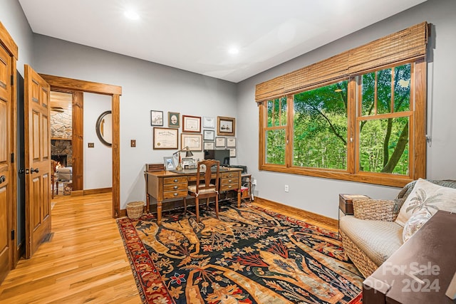 office space featuring a stone fireplace and light hardwood / wood-style flooring