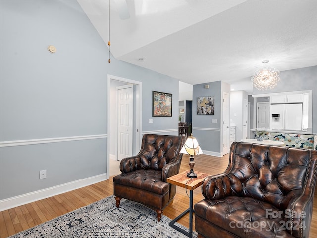 living room featuring hardwood / wood-style floors, ceiling fan with notable chandelier, and lofted ceiling