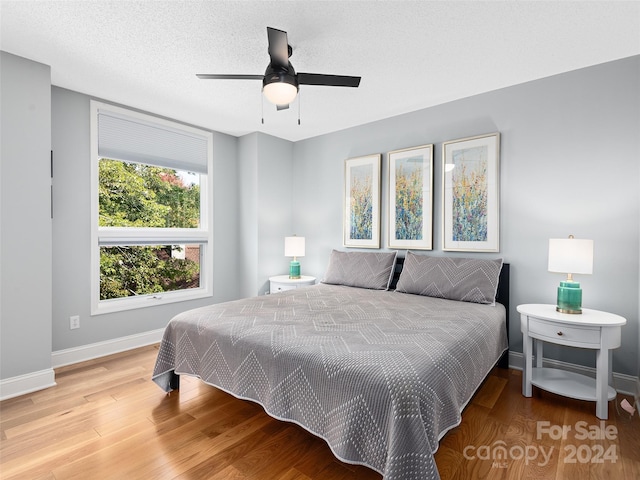 bedroom with wood-type flooring, a textured ceiling, and ceiling fan