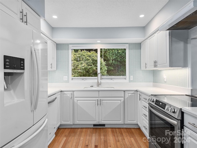 kitchen featuring white cabinets, light wood-type flooring, white appliances, and sink