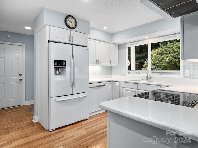 kitchen featuring sink, light hardwood / wood-style flooring, backsplash, white appliances, and white cabinets