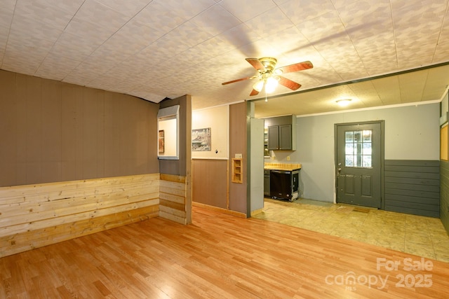 spare room with ceiling fan, wooden walls, and light wood-type flooring