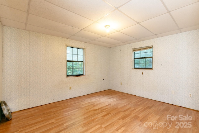 unfurnished room featuring a paneled ceiling, plenty of natural light, and hardwood / wood-style floors