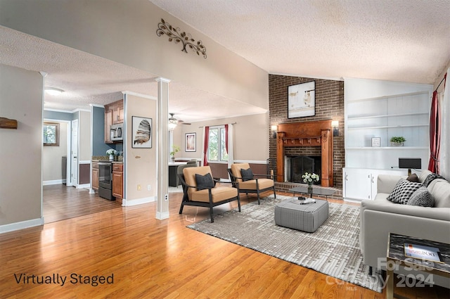 living room with lofted ceiling, hardwood / wood-style flooring, a brick fireplace, built in features, and a textured ceiling