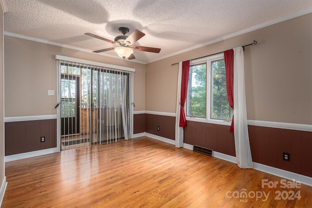 empty room featuring crown molding, a textured ceiling, light wood-type flooring, and ceiling fan