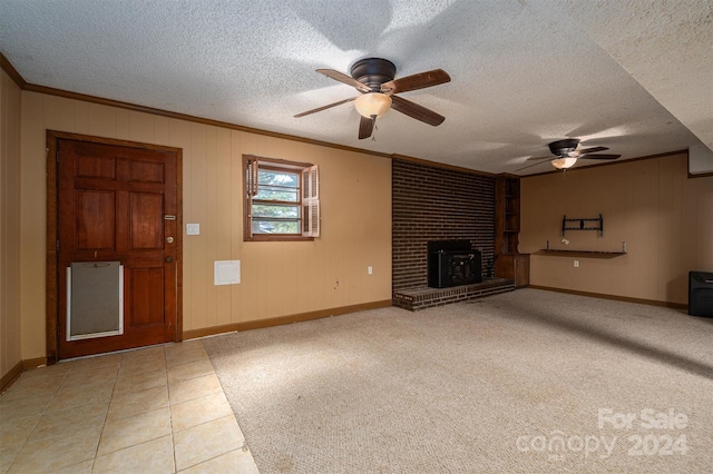 unfurnished living room featuring ceiling fan, light tile patterned flooring, a wood stove, and a textured ceiling