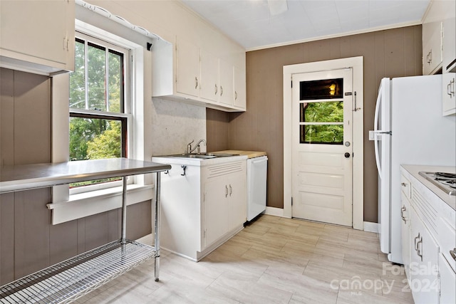 kitchen with white cabinetry, wood walls, and sink