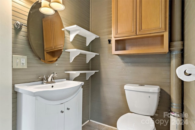 bathroom with wooden walls, tile patterned floors, vanity, and toilet