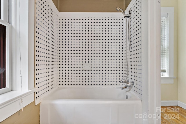 bathroom with a healthy amount of sunlight, shower / bathtub combination, and hardwood / wood-style flooring