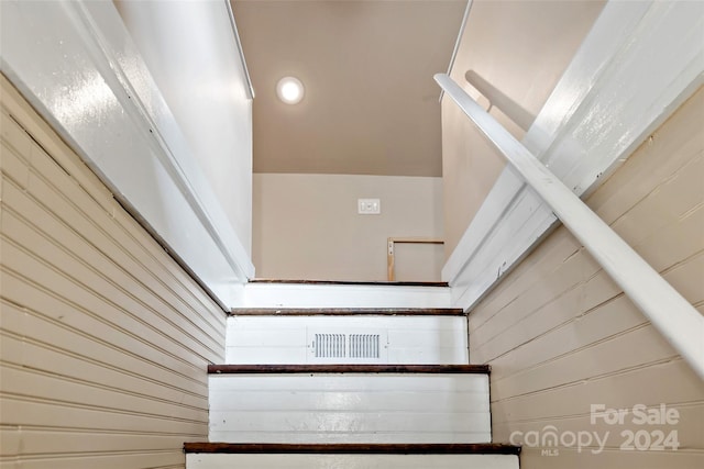 staircase featuring wood walls