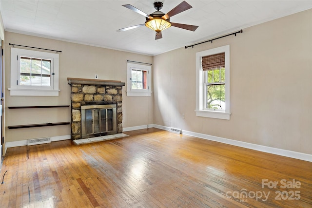 unfurnished living room with a stone fireplace, hardwood / wood-style floors, and ceiling fan